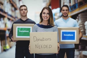 Volunteers smiling at camera holding donations boxes in a large warehouse - fundsforNGOs Accountability Incubator 2017-18: Lunch Your Idea for Building a more Accountable SOC