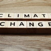 Wooden letter blocks spell 'CLIMATE CHANGE' on a wooden surface, illustrating the environmental issue.