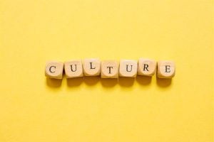 Wooden letter blocks spell out 'CULTURE' on a bright yellow background