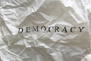 Crumpled white paper with the word DEMOCRACY in black letters.