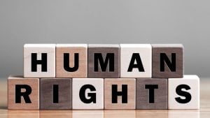 Wooden letter blocks spell 'HUMAN RIGHTS' on a wooden table, arranged in two rows.