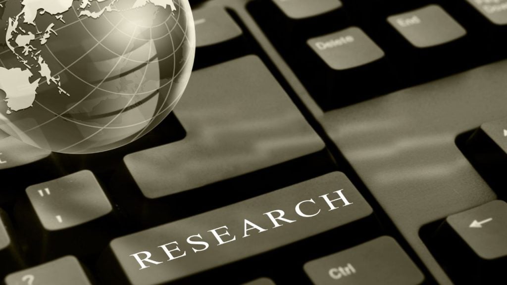Keyboard close-up with a bold 'RESEARCH' key and a globe graphic beside it, symbolizing online research