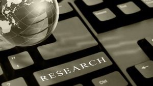 Keyboard close-up with a bold 'RESEARCH' key and a globe graphic beside it, symbolizing online research