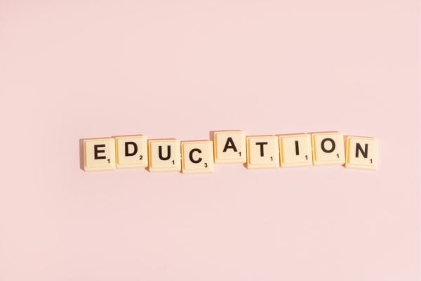 education - fundsforNGOs Scrabble tiles spell 'EDUCATION' on a soft pink background.