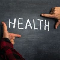 health 1 - fundsforNGOs Hands frame the word HEALTH written in chalk on a dark chalkboard edge.