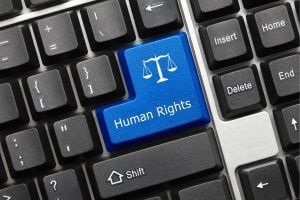 Blue keyboard key labeled 'Human Rights' with scales icon, among other keys. Represents advocacy or rights-related action on a keyboard.