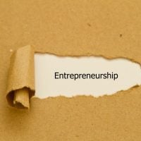 Entrepreneurship - fundsforNGOs Torn white strip reveals the word Entrepreneurship on a brown kraft background.