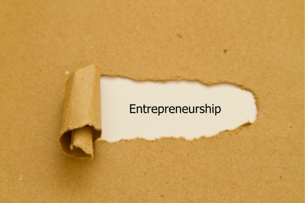Entrepreneurship - fundsforNGOs Torn white strip reveals the word Entrepreneurship on a brown kraft background.
