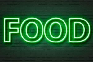 Bright green neon sign spelling 'FOOD' on a dark brick wall.