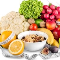FOOD - fundsforNGOs Colorful assortment of fruits and vegetables surrounding a bowl of granola, with a measuring tape draped around—symbolizing healthy eating and dieting.