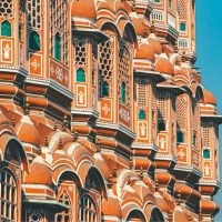 Heritage and Culture - fundsforNGOs Ornate orange palace facade with repeating arched windows and white detailing against a clear blue sky sincely bright light.