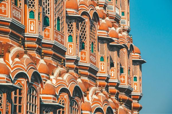 Heritage and Culture - fundsforNGOs Ornate orange palace facade with repeating arched windows and white detailing against a clear blue sky sincely bright light.