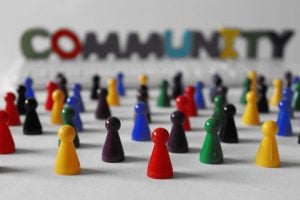Colorful pins arranged as a diverse community with the word COMMUNITY blurred in the background, symbolizing inclusion and belonging.