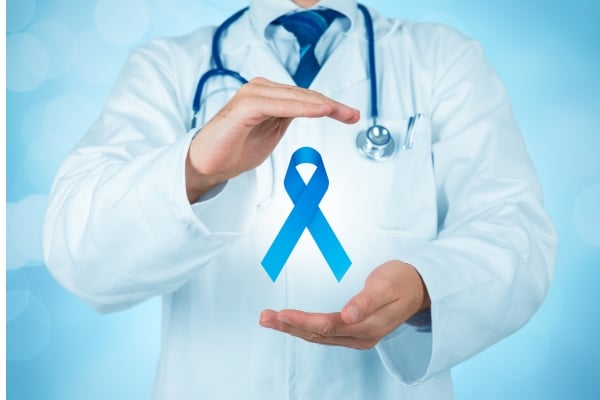 Marine Conservation 13 - fundsforNGOs Doctor in a white coat and stethoscope holding a blue cancer-awareness ribbon, symbolizing support and awareness.