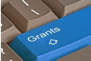 Blue keyboard key labeled 'Grants' with a cursor icon, symbolizing grant applications