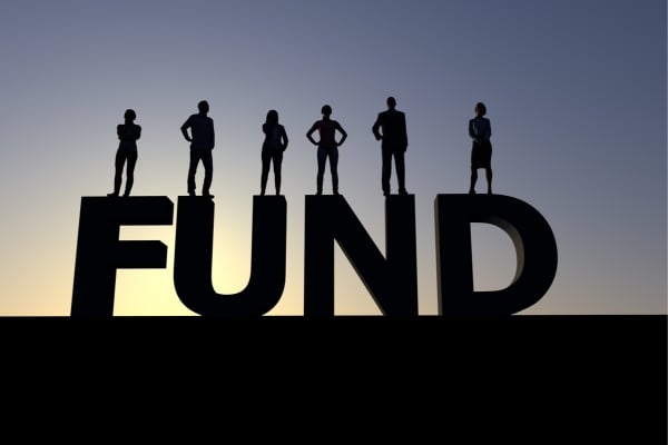 Marine Conservation 2 - fundsforNGOs Silhouetted team stands on large letters spelling 'FUND' against sunset, symbolizing funding and teamwork.