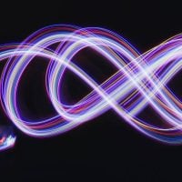 Quantum Technologies - fundsforNGOs Long-exposure light painting forming a neon infinity symbol in purple, blue, and pink against a dark background.