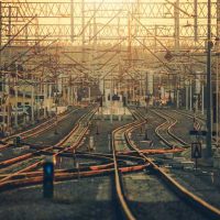 Rail Infrastructure - fundsforNGOs Rail yard with many parallel and intersecting train tracks under overhead electric lines at sunset.