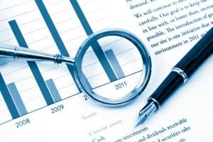 Bar chart of financial data from 2008–2011 with a magnifying glass over the 2011 bar and a pen nearby.