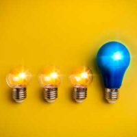 Technologies and Innovation - fundsforNGOs Four light bulbs in a row on a yellow background; three small incandescent bulbs lit and one larger blue bulb lit on the right.