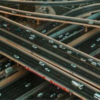 Transport - fundsforNGOs Bird's-eye view of a multi-level highway interchange with many lanes and vehicles in motion, showing complex ramps and overpasses in urban traffic.