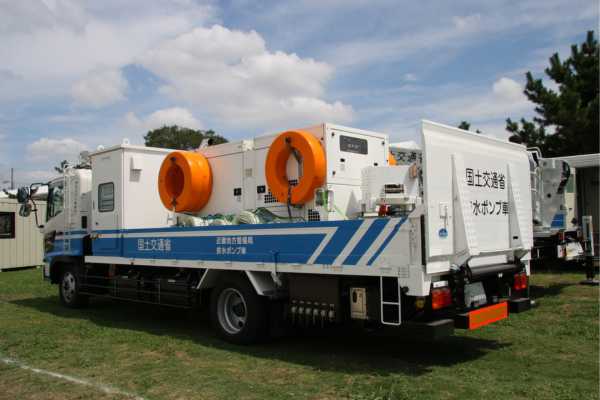 Transport Infrastructure - fundsforNGOs Large white utility truck with orange circular winches mounted on top, blue stripe and Japanese text, parked on a grassy field.