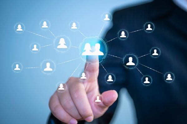business 7 - fundsforNGOs Hand touching a glowing central avatar in a network of interconnected user icons, symbolizing social or professional networking