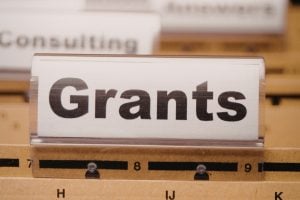 Close-up of a filing label reading 'Grants' with a blurred 'Consulting' label in the background.