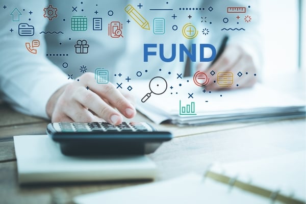 Close-up of a person using a calculator with documents; blue finance icons and the word FUND overlaid, signaling budgeting and funding.