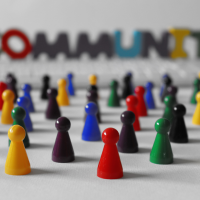 community 1 - fundsforNGOs A group of colorful pawn figures representing a diverse community, with the word COMMUNITY blurred in the background.