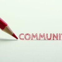 community 3 - fundsforNGOs Red pencil drawing the word COMMUNITY on a white surface.