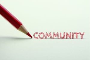 Red pencil drawing the word COMMUNITY on a white surface.