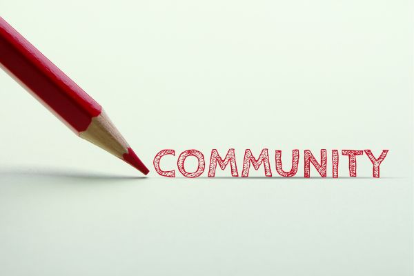 community 3 - fundsforNGOs Red pencil drawing the word COMMUNITY on a white surface.