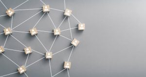 Wooden blocks with user icons connected by white lines forming a social/network graph on a gray background, representing connectivity between people.