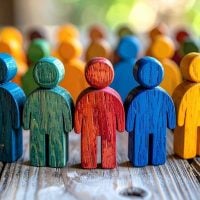 Colorful wooden human figurines lined up, symbolizing diversity and teamwork.