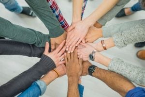 Group of diverse hands stacked together in the center, representing teamwork and unity.