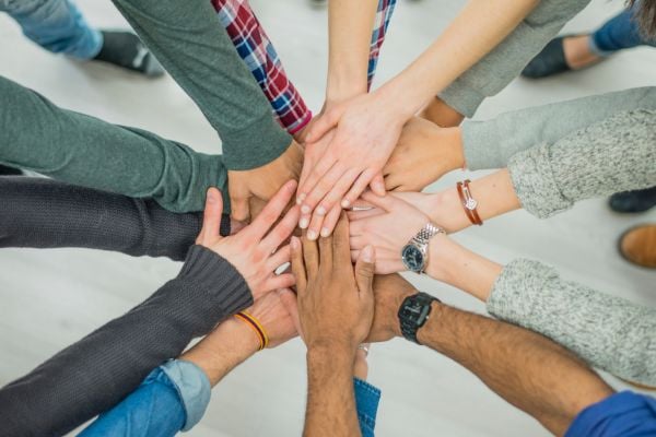community 7 - fundsforNGOs Group of diverse hands stacked together in the center, representing teamwork and unity.