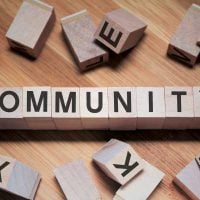 community 9 - fundsforNGOs Wooden letter blocks spell COMMUNITY on a wooden surface with loose blocks scattered around.