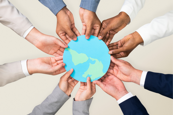 Diverse hands join around a blue globe, symbolizing global cooperation and unity.
