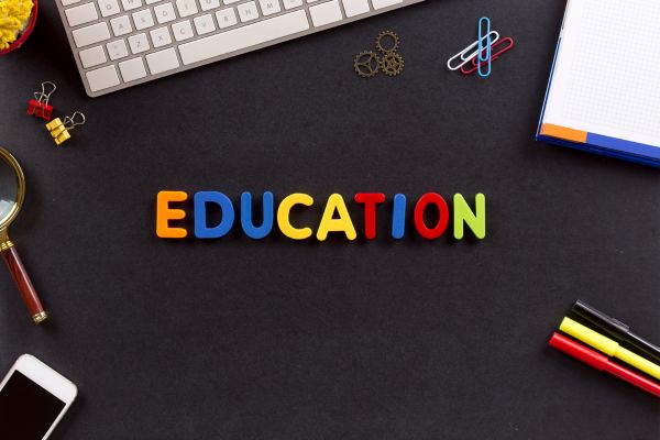 education 1 - fundsforNGOs Colorful letters spelling EDUCATION on a dark desk with keyboard, notebook, paperclips, and markers nearby