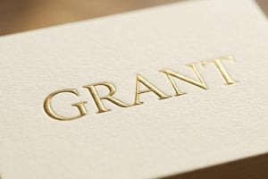 Close-up of a cream-colored card with the word GRANT embossed in gold lettering.