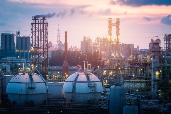 fundsforNGOs - 2026-06-01T150426981 - fundsforNGOs Industrial refinery complex at dusk with smokestacks, storage tanks, and lattice structures bathed in sunset light.
