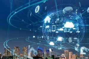 Smart city skyline at dusk with holographic network icons and cloud imagery representing IoT and connectivity.