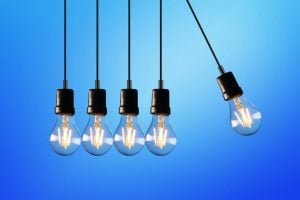Five hanging light bulbs in a row with one tilted to the right against a blue gradient background.