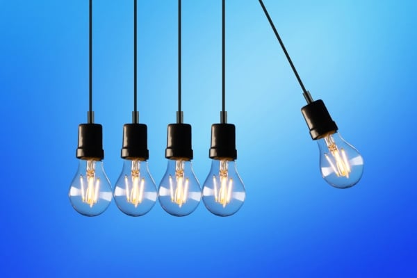 Five hanging light bulbs in a row with one tilted to the right against a blue gradient background.