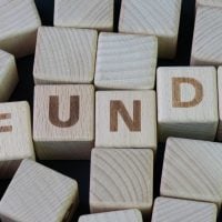 fundsforNGOs - 2026-06-04T124411071 - fundsforNGOs Wooden blocks arranged to spell FUNDS on a dark surface.