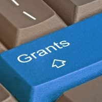 fundsforNGOs - 2026-06-04T152714502 - fundsforNGOs Blue keyboard key labeled 'Grants' with a cursor icon among brown keys, shown in a close-up.