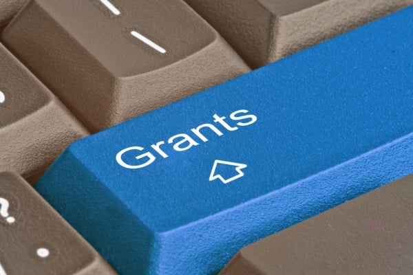 Blue keyboard key labeled 'Grants' with a cursor icon among brown keys, shown in a close-up.