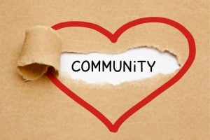Cardboard background with a red heart outline torn open to reveal the word COMMUNITY on white paper