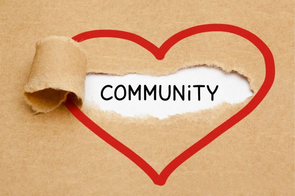 Cardboard background with a red heart outline torn open to reveal the word COMMUNITY on white paper